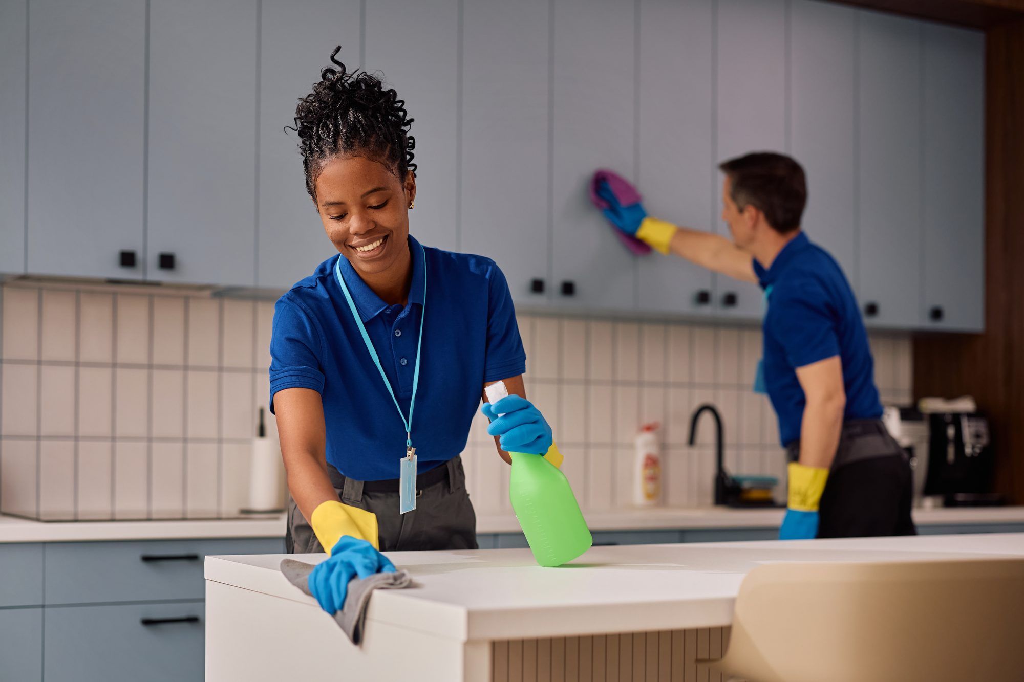 Colaboradora da Fada Madrinha, de polo azul, a limpar a bancada de uma cozinha